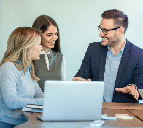 Business team discussing sales strategies around a laptop.