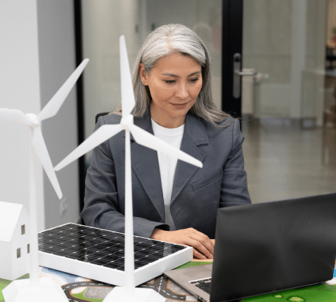 Professional woman working on energy sales outsourcing project with wind turbine models.